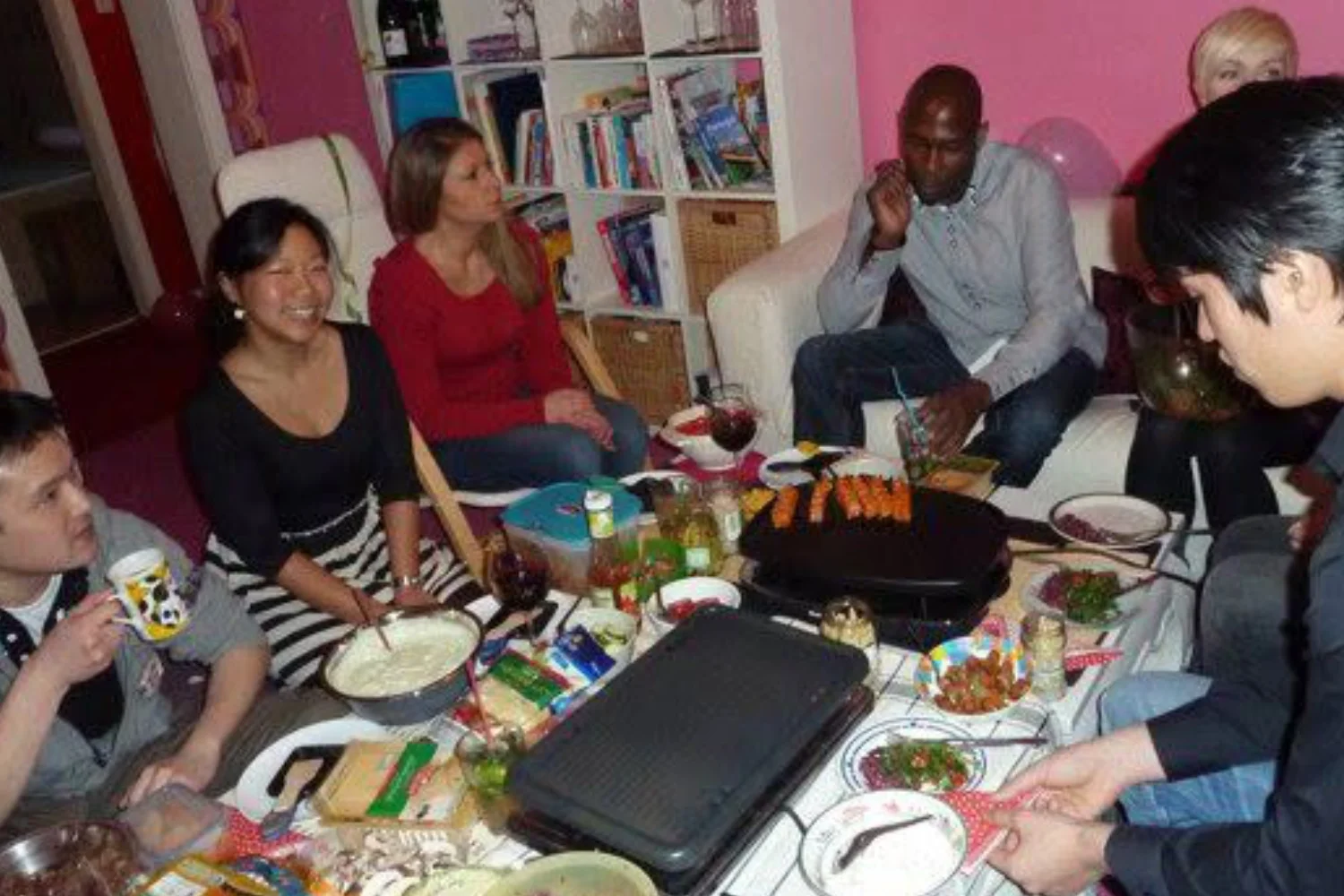 Nui and friends enjoying a cozy home raclette party around a food-filled table in Hannover.