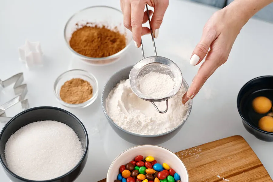 Baking ingredients: flour being sifted, sugar, cocoa, eggs, and colorful candies.