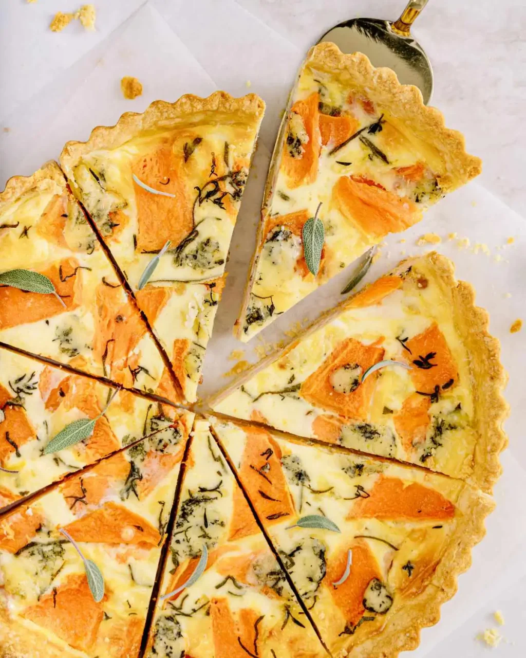 Butternut squash and sage quiche slices on parchment paper.