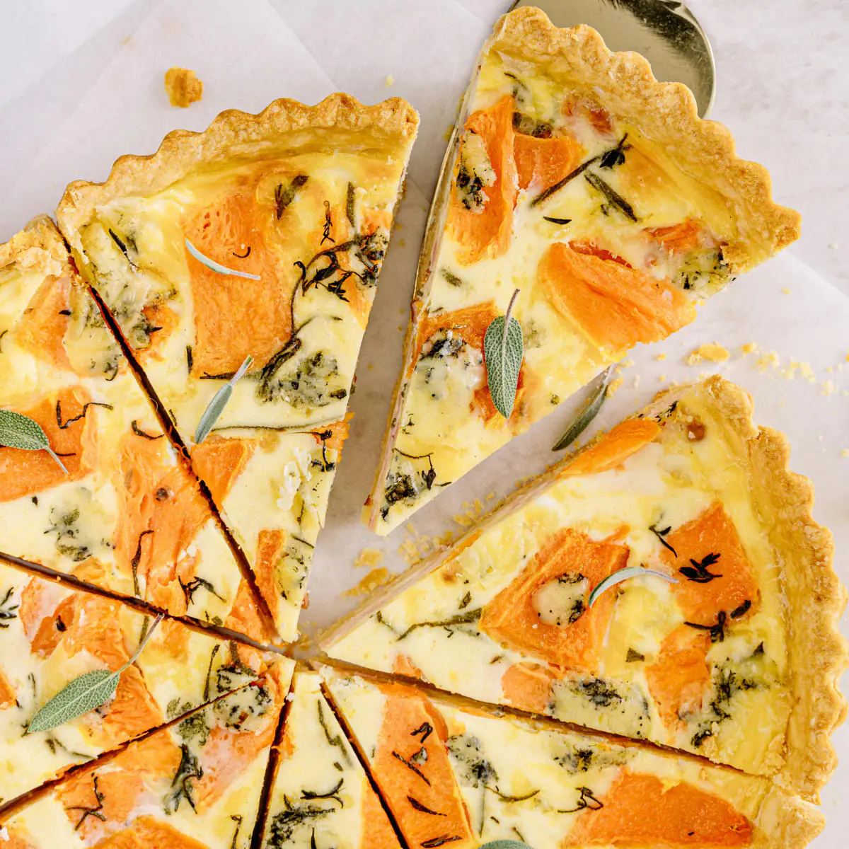 Sliced butternut squash tart with sage, close-up view.