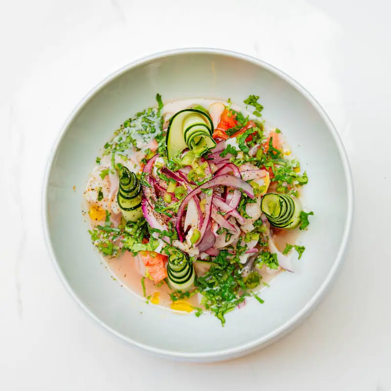 Bowl of ceviche with cucumber, red onion, and cilantro garnish.