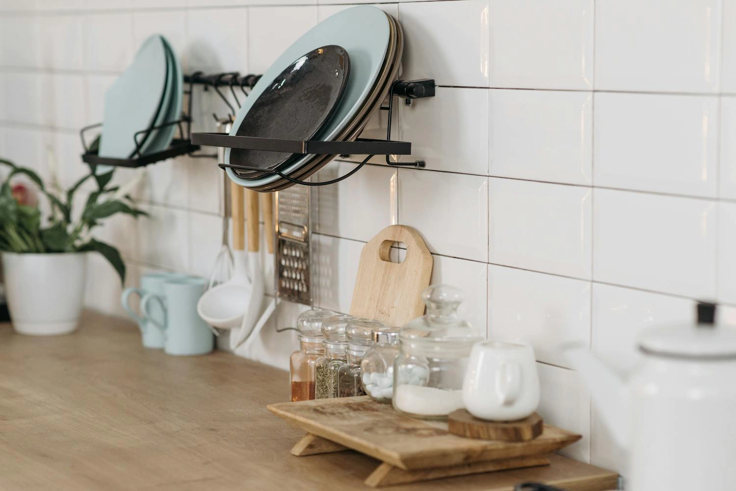 Kitchen counter with dish rack, utensils, spices, and wooden cutting board.