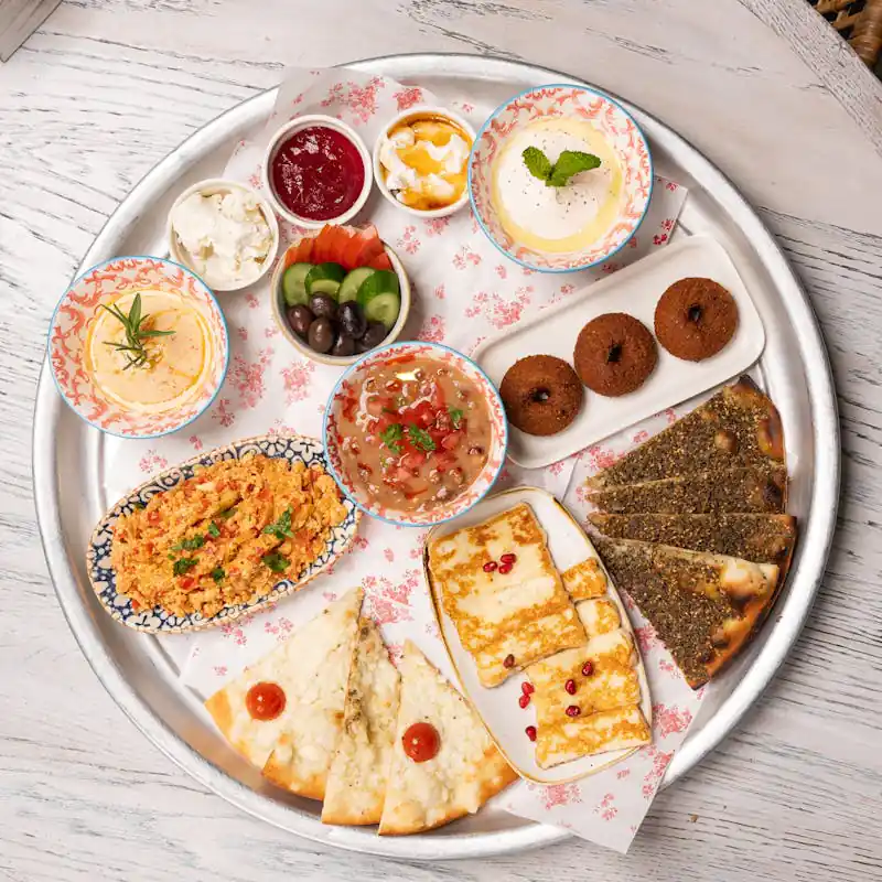 Lebanese breakfast platter with dips, pastries, cheese, & vegetables.