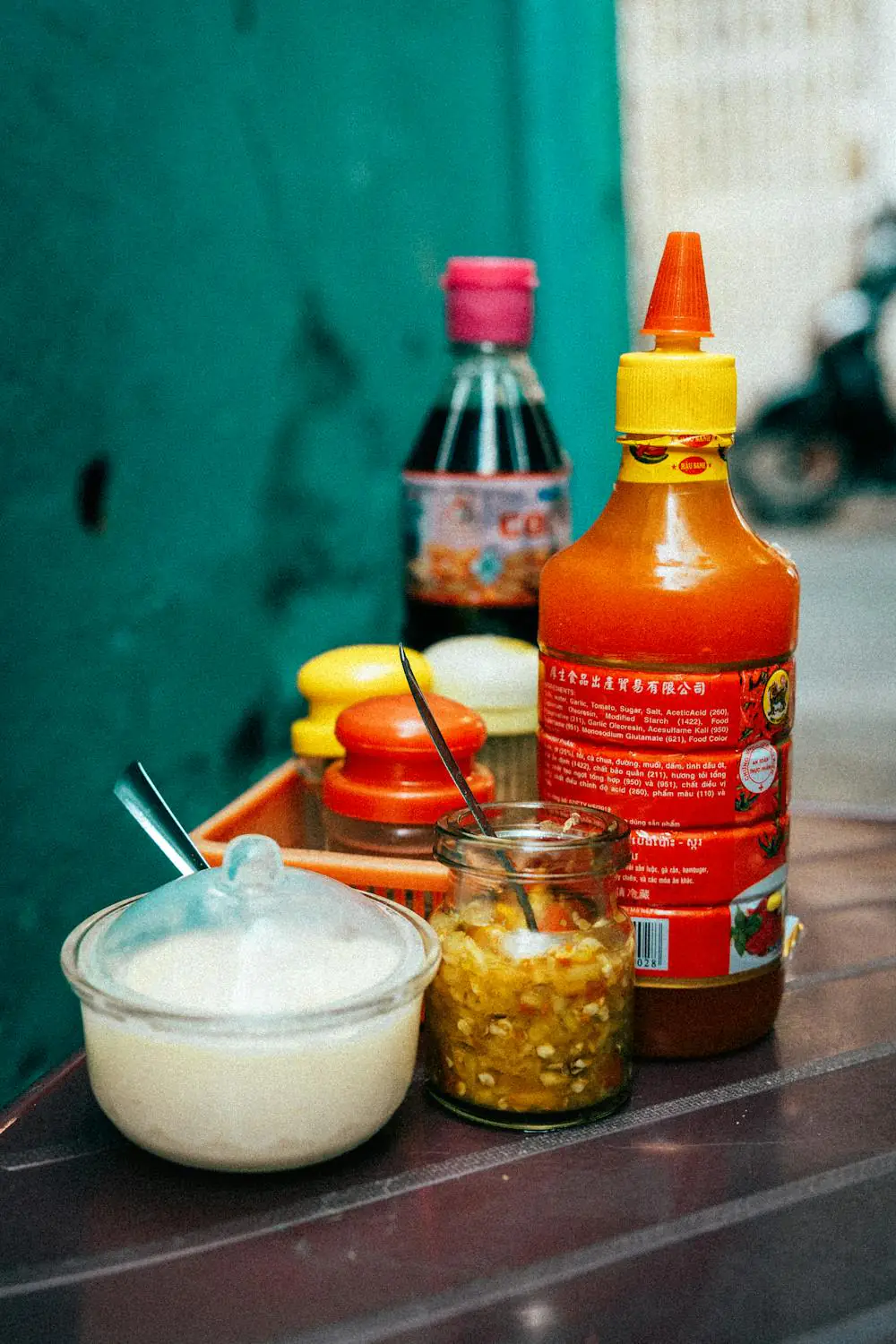 Vietnamese condiments: chili sauce, garlic, and dipping sauces on a table.