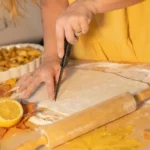 Woman cutting pie crust with knife, apple pie filling, fall leaves.